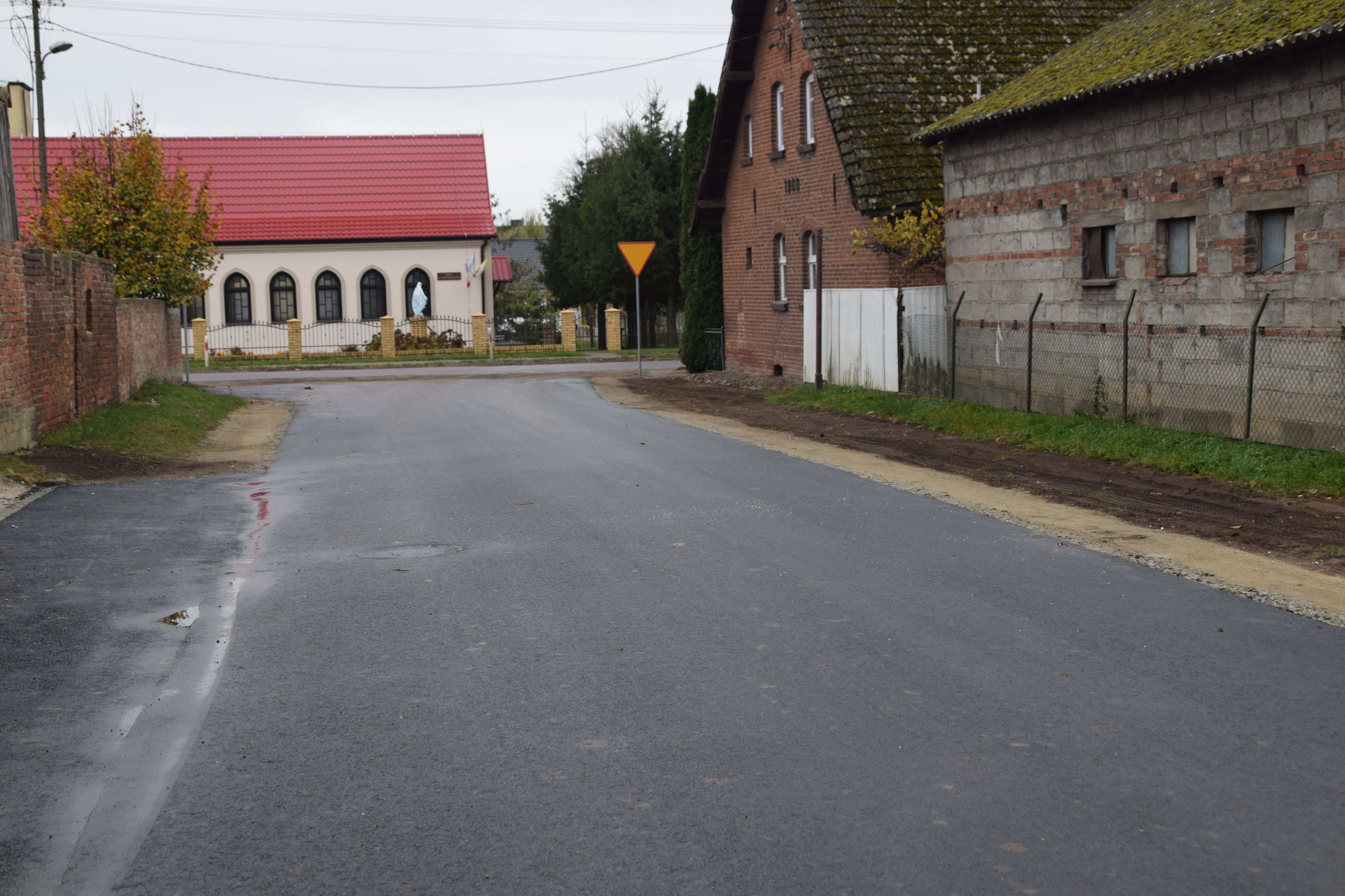 widok na&nbsp;nową, ryremontowaną droga gminna w&nbsp;Skrzetuszu, po bokach zabudowania gospodarcze a&nbsp;na przeciwko kaplica w&nbsp;Skrzetuszu