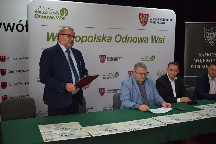 na zdjęciu znajduje się Wójt Gminy Ryczywół trzymający w ręce teczkę obok siedzi Wicemarszałek Województwa Wielkopolskiego, Wiceprzewodniczący Sejmiku Województwa Wielkopolskiego oraz Poseł na Sejm RP
